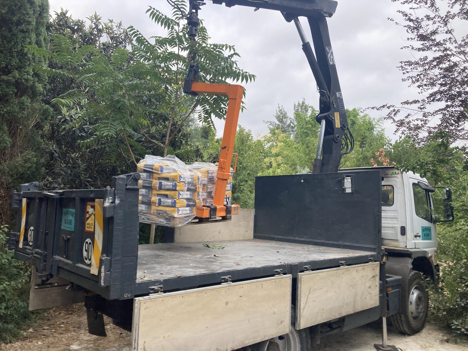 Dépose de palette de matériaux à l'étage avec camion grue Transport Blache