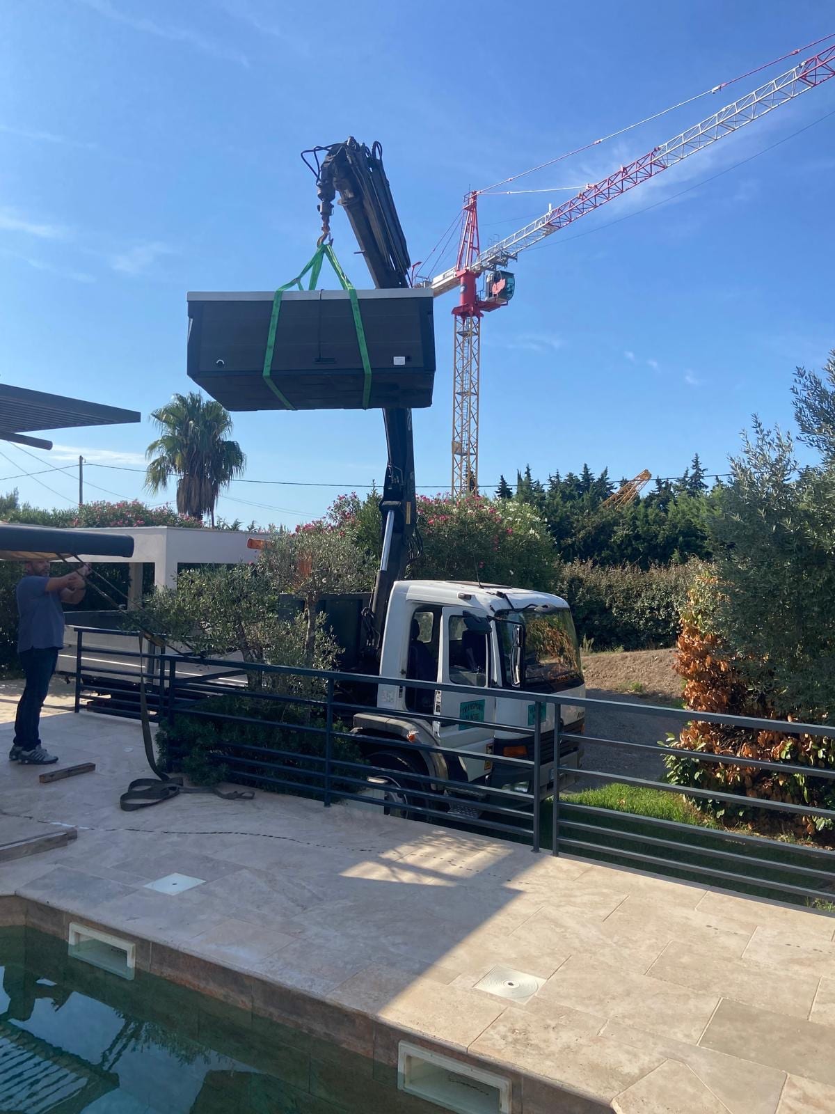 Levage d'un spa près d'une piscine avec le camion grue Transport Blache