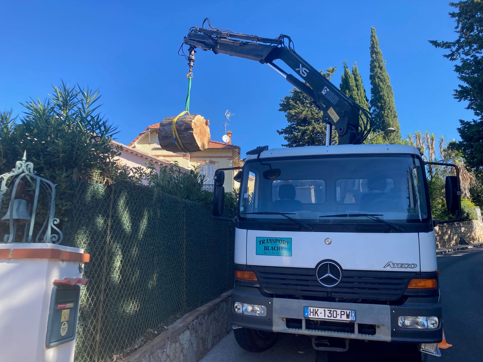 Levage d'un tronc d'arbre en accès difficile avec le camion grue Transport Blache